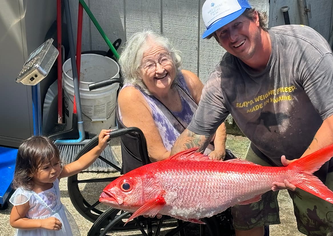 Man with older woman and child, holding fish.