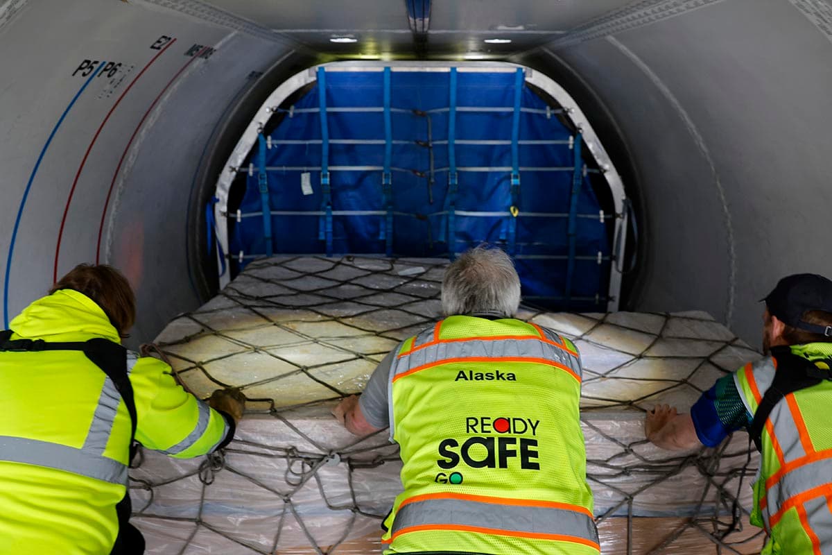 Three men in yellow vests load a freighter 737