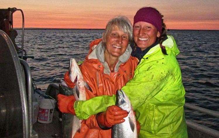Adult mother and daughter with salmon on boat in Bristol Bay