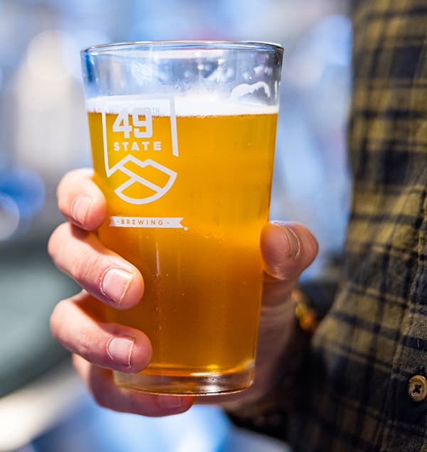 Pint of beer with 49th State Brewing logo