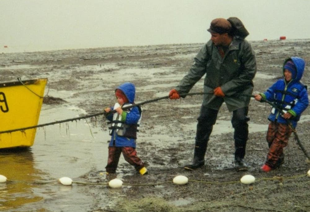 Two boys with dad pulling on a running line for a boat.